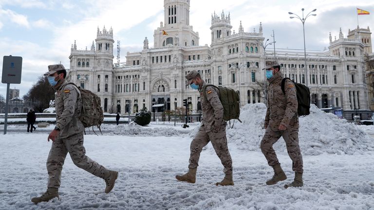 Members of the military walk past the Cibeles fountain and the City Hall building after a heavy snowfall in Madrid, Spain January 10, 2021. REUTERS/Susana Vera
