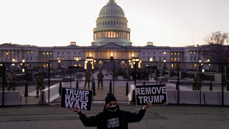 A protester holds signs near the US Capitol calling for the removal of Mr Trump