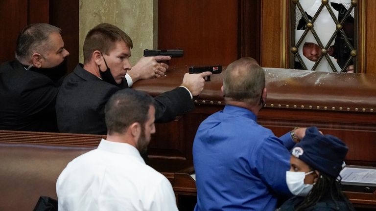 U.S. Capitol Police with guns drawn watch as protesters try to break into the House Chamber at the U.S. Capitol on Wednesday, Jan. 6, 2021, in Washington. (AP Photo/J. Scott Applewhite)                                                                                                       