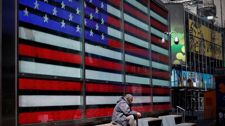 مردی بی خانمان به تنهایی در میدان تایمز تقریبا خالی در منهتن در طول شیوع بیماری کرونا (COVID-19) در شهر نیویورک، نیویورک، ایالات متحده، 7 آوریل 2020 نشسته است.
