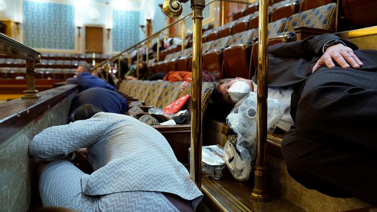 People shelter in the House gallery as protesters try to break into the House Chamber at the U.S. Capitol on Wednesday, Jan. 6, 2021, in Washington. (AP Photo/Andrew Harnik)                                                                                       