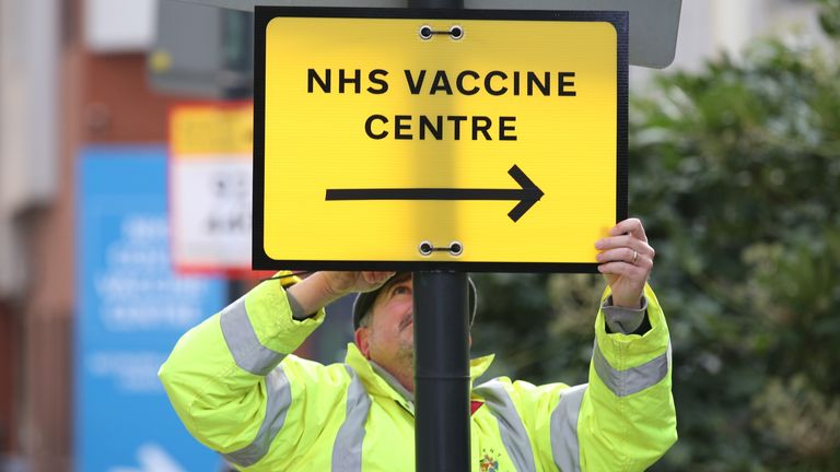 A Brent Council worker hangs a direction sign to the NHS Covid Vaccine Centre at the Olympic Office Centre, Wembley, north London, as ten further mass vaccination centres opened in England with more than a million over-80s invited to receive their coronavirus jab. Picture date: Monday January 18, 2021.