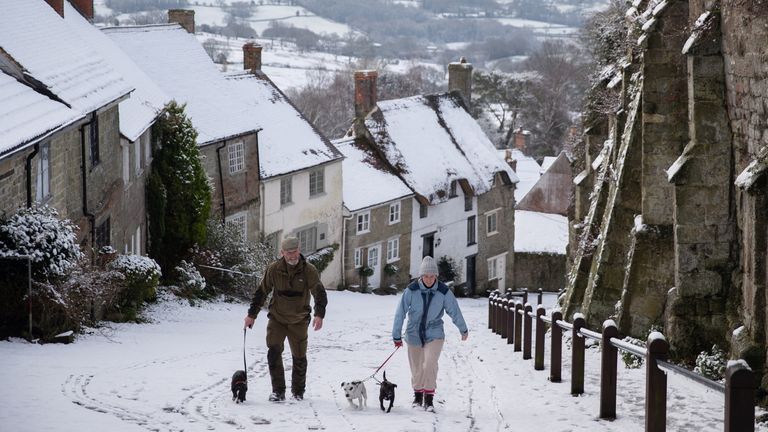 Dog walkers on a snowy Gold Hill, in Shaftesbury, Dorset