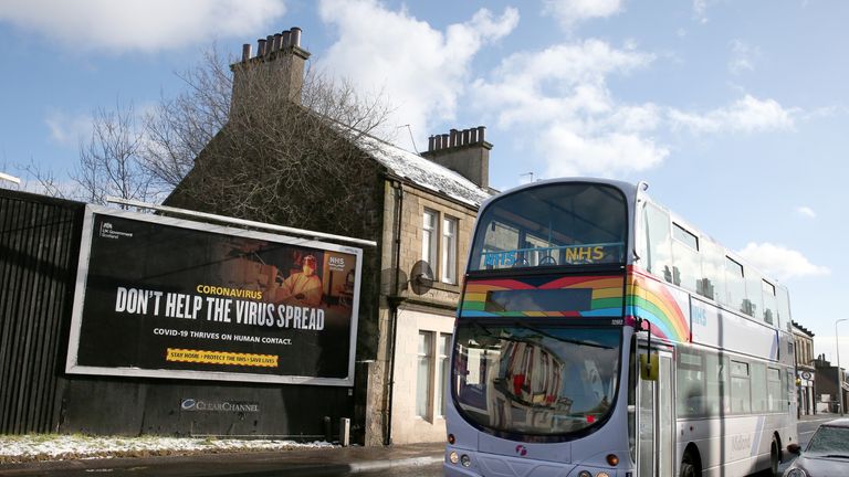 Un bus décoré d'un arc-en-ciel et d'autocollants du NHS fait passer une publicité liée au coronavirus sur un panneau d'affichage à Falkirk, dans le centre de l'Écosse, où les mesures de verrouillage introduites le 5 janvier pour l'Écosse continentale restent en vigueur au moins jusqu'à la fin du mois de février.  Date de la photo: lundi 8 février 2021.