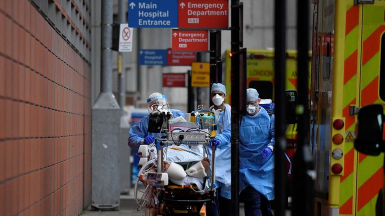 Medical workers move a patient between ambulances outside the Royal London Hospital
