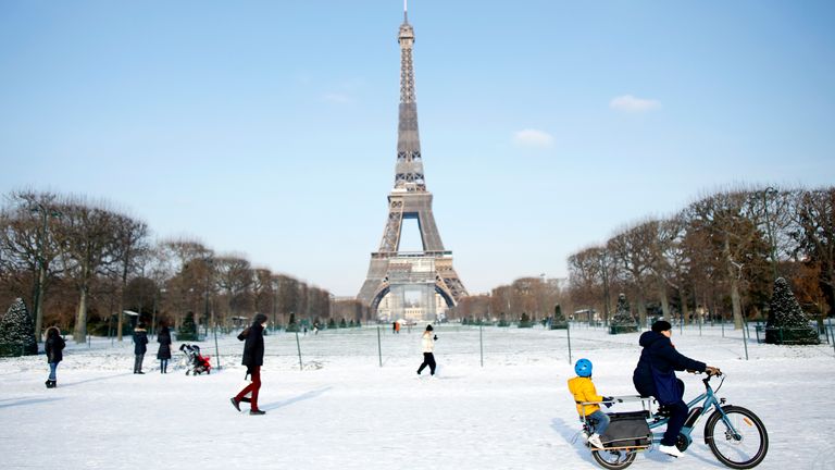 People walk and cycle on a snow covered alley near the Eiffel Tower in Paris, France. Pic: AP