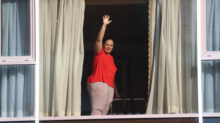 Passenger Andressa Pelosini, 43, waves from inside the Radisson Blu Edwardian Hotel at Heathrow