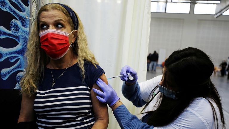 FILE PHOTO: A woman receives a vaccination against the coronavirus disease (COVID-19) at a temporary Clalit healthcare maintenance organisation (HMO) centre, at a basketball court in Petah Tikva, Israel January 28, 2021. REUTERS/Ammar Awad/File Photo