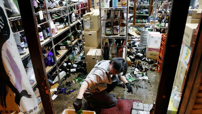 The manager of a liquor store cleans up broken bottles in the city of Fukushima on Feb. 13, 2021, after a strong earthquake with a preliminary magnitude of 7.1 rocked northeastern Japan. (Kyodo via AP Images) ==Kyodo