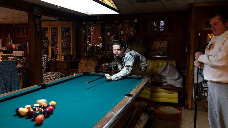 Joe DiMeo plays pool with his father John at their home, Thursday, Jan. 28, 2021, in Clark, N.J., six months after an extremely rare double hand and face transplant. Back in 2018, DiMeo fell asleep at the wheel, he said, losing control of his car, which hit a curb and utility pole, flipped over, and burst into flames. (AP Photo/Mark Lennihan)