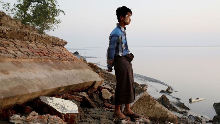 A student stands near the rubble of a school after it collapsed into the water in Myanmar