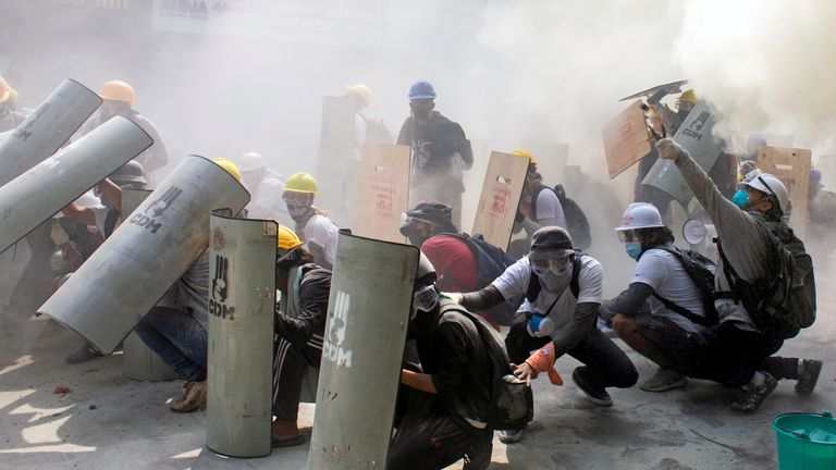 Protesters take cover as they clash with riot police officers