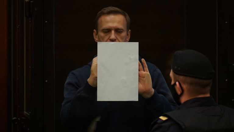 The 44-year-old places a piece of paper on the inside of his glass pod in court