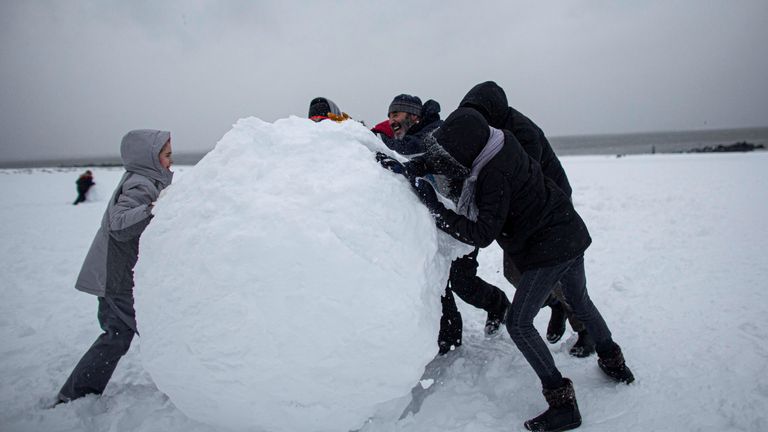 People make a giant snow ball during a winter storm in the New York suburb of Brighton Beach