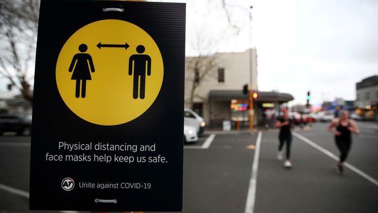 FILE PHOTO: People jog past a social distancing sign in Auckland, New Zealand, August 31, 2020