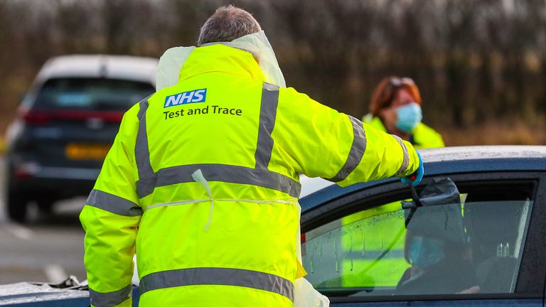 An NHS Test and Trace worker hands a person a test kit in a drive-through testing centre in Southport