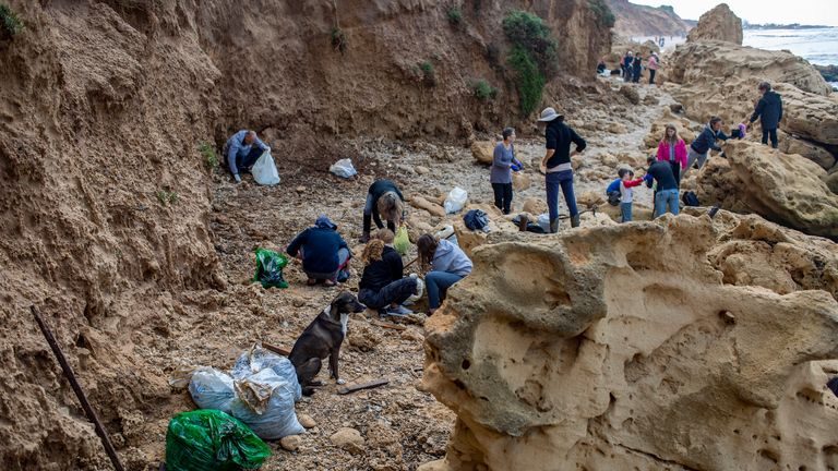 الناس ينظفون القطران من التسرب النفطي في البحر الأبيض المتوسط ​​في محمية جادور الطبيعية بالقرب من الخضيرة ، إسرائيل ، يوم السبت ، 20 فبراير ، 2021. يشارك مئات المتطوعين في عملية تنظيف للشاطئ الإسرائيلي حيث تجري التحقيقات لتحديد سبب تسرب النفط الذي يهدد الشاطئ والحياة البرية ، في محمية جادور الطبيعية بالقرب من مدينة الخضيرة الشمالية ، والأسماك الملطخة بالقطران ، والسلاحف ، وغيرها من الكائنات البحرية.  (AP Photo / Ariel Schalit)