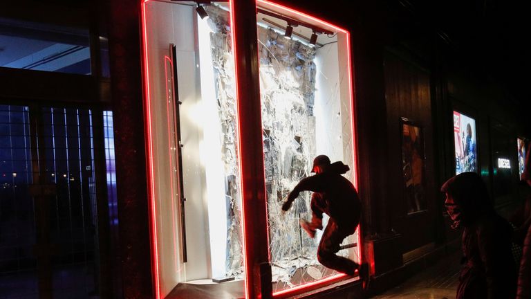 Un manifestant ouvre la fenêtre d'un magasin alors que les partisans du rappeur catalan arrêté Pablo Hasel manifestent à Barcelone, en Espagne, le 20 février 2021. REUTERS / Albert Gea TPX IMAGES DU JOUR