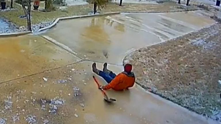Man slides down pathway with shovel after attempting to deal with slippery ice