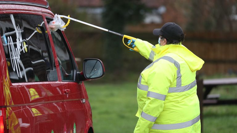 A test and trace worker in the Bramley Inn car park in Bramley, near Basingstoke, Hampshire takes a coronavirus test from a driver at a surge testing programme with local residents, after a case of the South African variant of Covid-19 was identified in the village. Picture date: Wednesday February 17, 2021.
