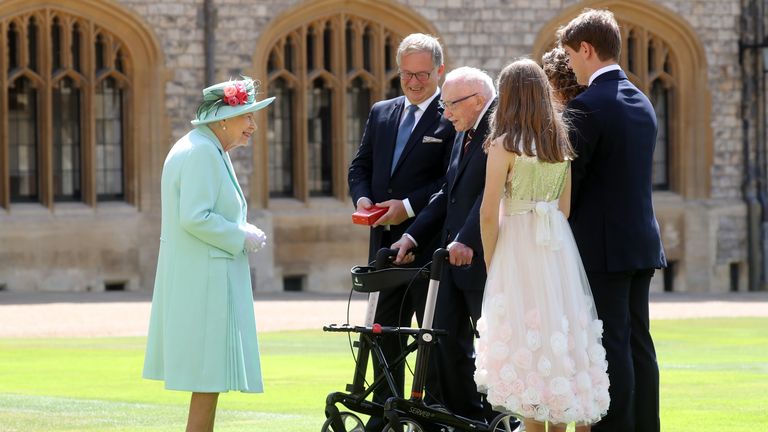 Queen Elizabeth II talks Captain Sir Thomas Moore and his family after awarding his knighthood during a ceremony at Windsor Castle.