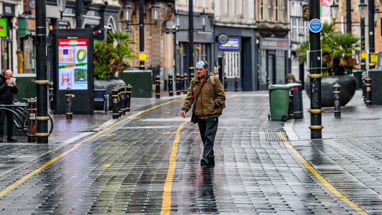 A man wears a facemask on his head in an almost empty central shopping area of Cardiff, Wales, where they are in alert level 4 lockdown on the first weekend of January sales, with many shops not open to browse.