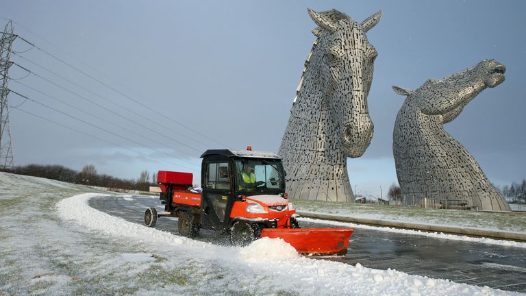 A staff member uses a vehicle to clear snow on a pathway at the Kelpies near Falkirk in Scotland