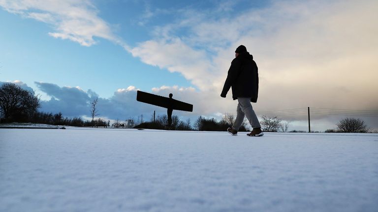 A member of the public is seen walking in the snow towards The Angel of the North in Gateshead, England, Monday, Feb. 8, 2021. Snow has swept across the region, with further snowfall predicted to impact on the country bringing travel problems as temperatures drop. (AP Photo/Scott Heppell)