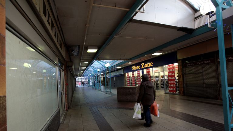 A woman walks past Shoe Zone, one of the only remaining shops open in the northern end of the Southside Shopping centre in Wandsworth, London, where retail units are closed awaiting redevelopment.