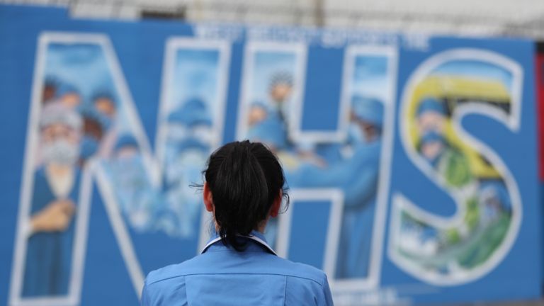 A nurse looks at a mural painted in recognition of the NHS on the Falls Road in Belfast, as the UK continues in lockdown to help curb the spread of the coronavirus.