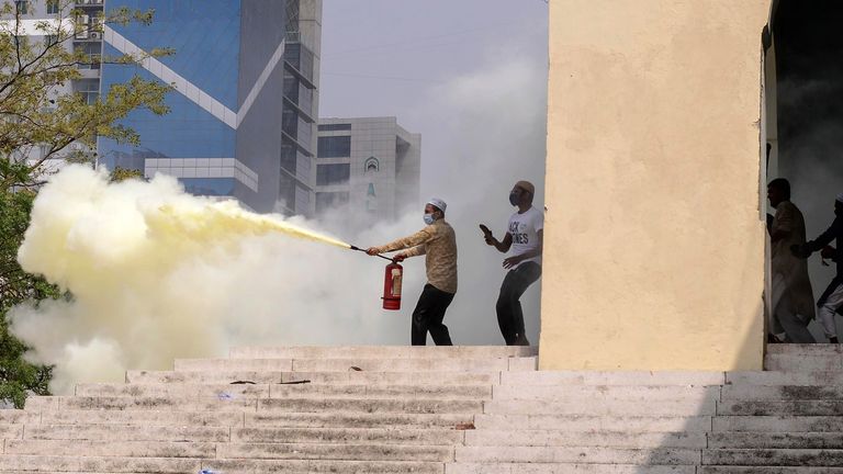 A group of protestors use fire extinguisher during a clash with another group outside a mosque in Dhaka
