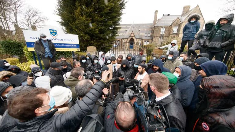 Protesters and media surround the school gates on Friday