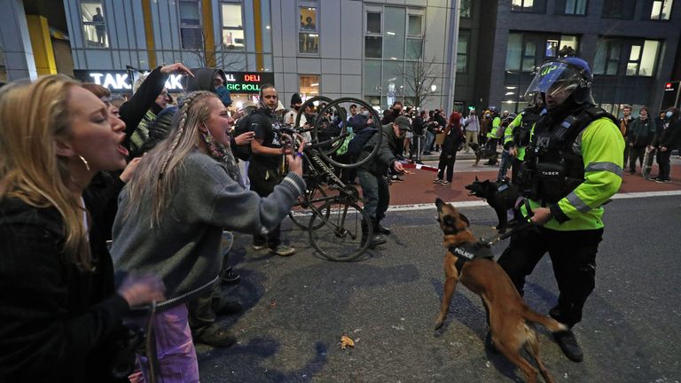 یک افسر پلیس با یک سگ پلیس در خارج از ایستگاه پلیس بریدول با معترضین روبرو می شود