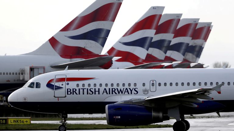 FILE PHOTO: A British Airways plane taxis past tail fins of parked aircraft near Terminal 5 at Heathrow Airport in London, Britain, March 14, 2020