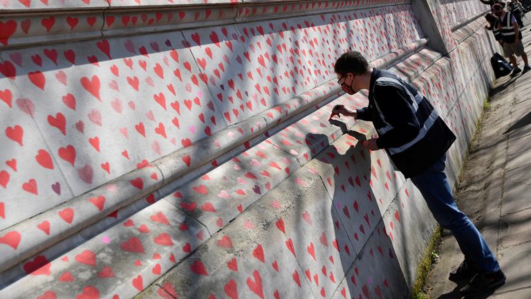 Volunteers and relatives of bereaved paint hearts along a wall beside St Thomas&#39; hospital as a memorial to all those who have died so far in the UK from COVID-19, amid the spread of the coronavirus disease pandemic in London, Britain, March 29, 2021. REUTERS/Toby Melville