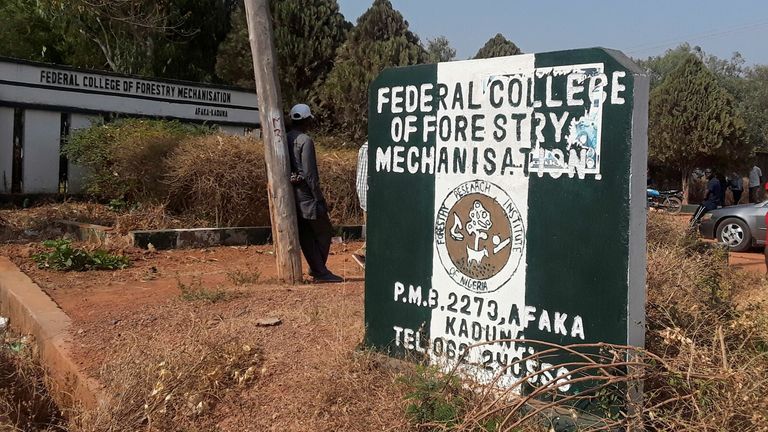 A man rests on a pole beside the signage of the Federal College of Forestry Mechanization where gunmen abducted students, 