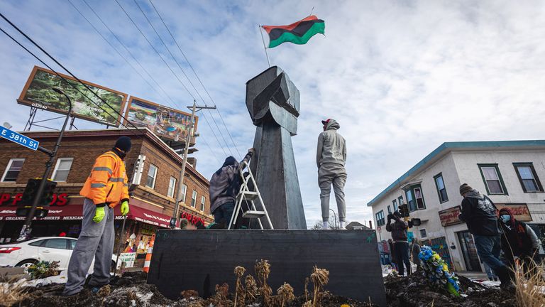 Artists and community members help erect a new fist statue in the square where Black man George Floyd died