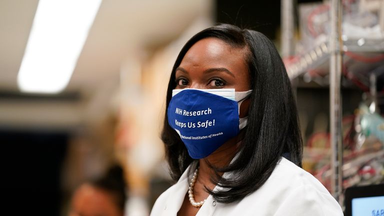 Kizzmekia Corbett, an immunologist with the Vaccine Research Center at the National Institutes of Health (NIH) looks on as President Joe Biden visits the Viral Pathogenesis Laboratory at the NIH, Thursday, Feb. 11, 2021, in Bethesda, Md. (AP Photo/Evan Vucci)
