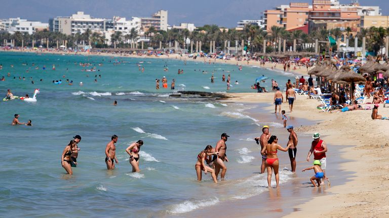 People sunbathe and swim on El Arenal beach in Palma de Mallorca