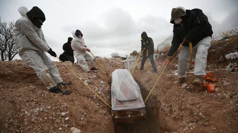 FILE - In this Oct. 27, 2020 file photo, workers wearing full protection gear amid the new coronavirus pandemic, lower a coffin into a grave in an area of the San Rafael municipal cemetery set apart for people who have died from COVID-19, in Ciudad Juarez, Mexico. As Mexico approaches 200,000 in officially test-confirmed deaths from COVID-19, the real death toll is probably higher due to the country’s extremely low rate of testing. (AP Photo/Christian Chavez, File)


