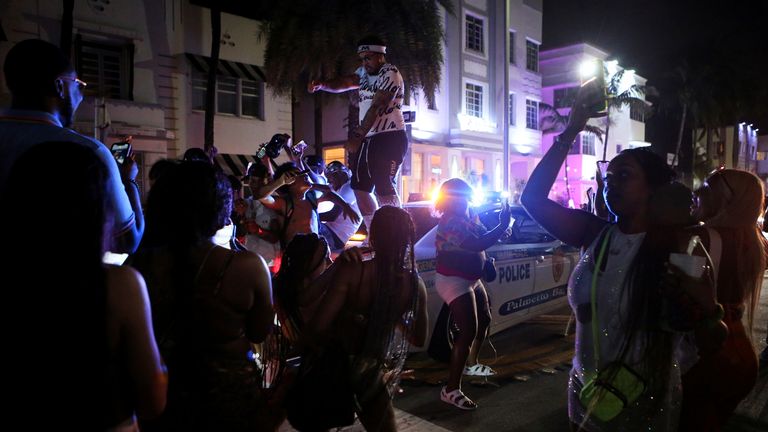 A man dances on top of a police car as revelers enjoy spring break festivities despite a 8pm curfew imposed by local authorities, amid the coronavirus disease (COVID-19) pandemic, in Miami Beach, Florida, U.S., March 20, 2021. REUTERS/Marco Bello