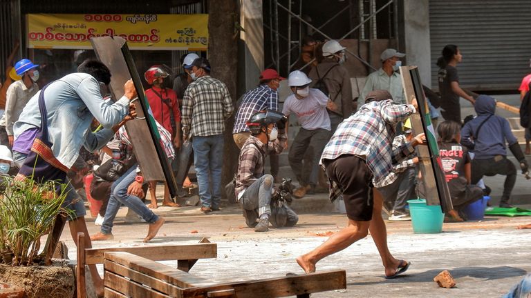 Protesters cover with makeshift shields during an anti-coup protest in Mandalay, Myanmar