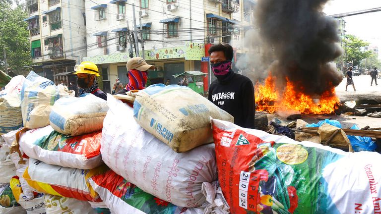 Anti-coup protesters take positions behind their makeshift barricade in a protest in Yangon, Myanmar