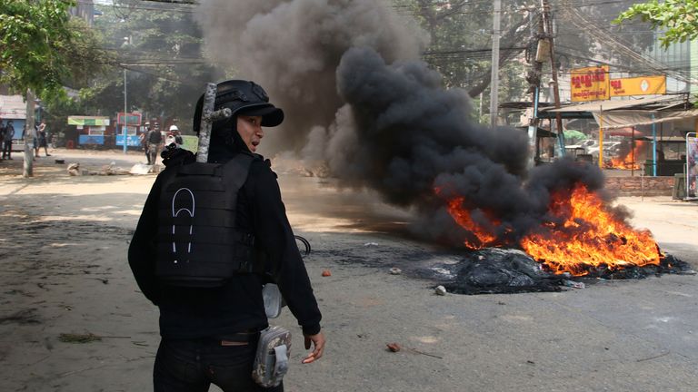 An anti-coup protester stands near a fire during a demonstration in Dala township, Yangon. Pic: AP