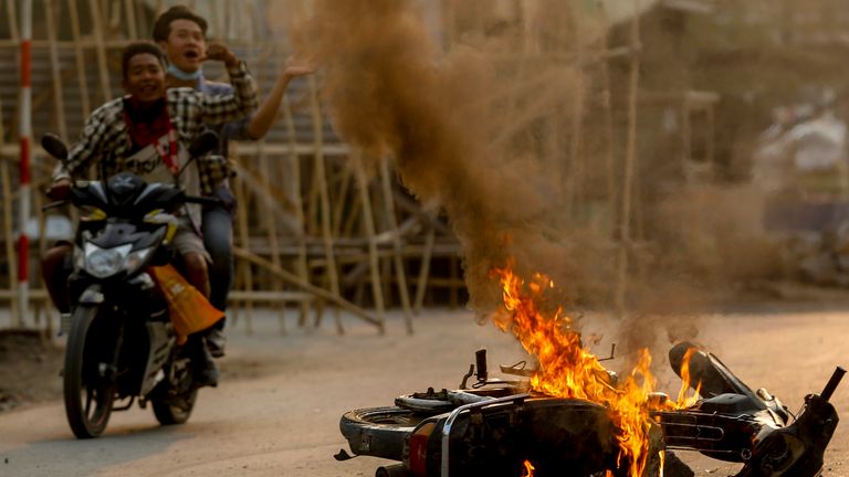 Two men on a motorbike warn protesters security forces are comingat a demonstration in Mandalay. Pic: AP