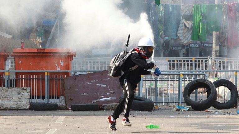 Un manifestant anti-coup pulvérise un extincteur près d'une barricade de la police à Yangon