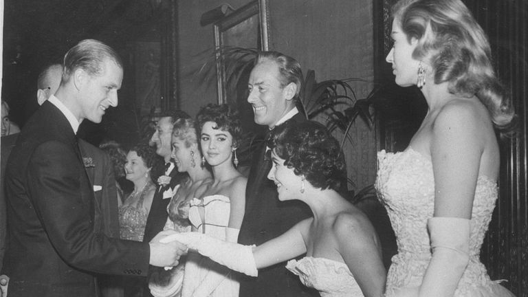 Actress Elizabeth Taylor curtsies as she is greeted by the Prince Philip, Duke of Edinburgh at the premiere of 