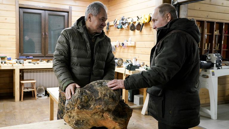 Russia Defense Minister Sergei Shoigu, left, and Russian President Vladimir Putin talk to each other and look at a piece of wood for crafting at Sergei Shoigu&#39;s workroom in a taiga forest in Russia&#39;s Siberian region in Russia. 