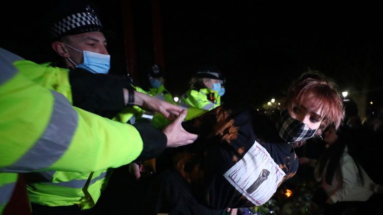 Police detain a woman as people gather at a memorial site in Clapham Common Bandstand, following the kidnap and murder of Sarah Everard, in London, Britain March 13, 2021. REUTERS/Hannah McKay
