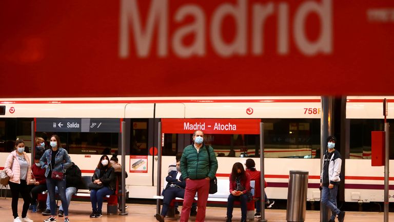 Commuters wear protective face masks wait on a platform at Atocha train station in Madrid